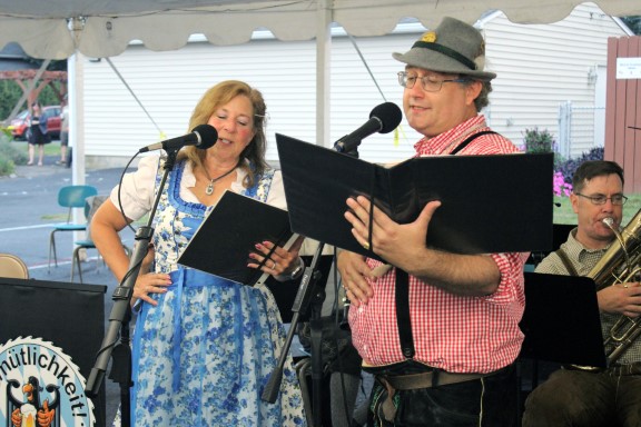 Two singers at a microphone with sheet music
